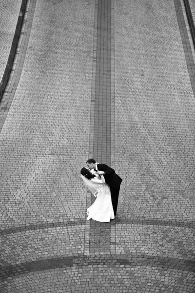 Blick von oben auf den Bräutigam, der eine Braut auf der grauen Straße küsst — Stockfoto