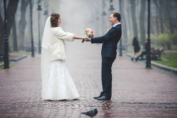 Hochzeitspaar wirbelt auf regennasser Straße im Park — Stockfoto