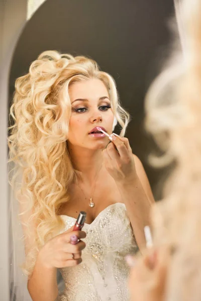 Блондинка невеста выглядит соблазнительно, рисуя губы. — стоковое фото