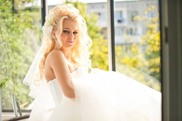 Hinreißende Braut mit blonden Haaren sitzt auf der Fensterbank — Stockfoto