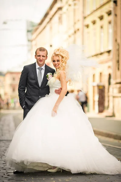 Krullend bruid glimlacht permanent achter een bruidegom in grijs pak — Stockfoto