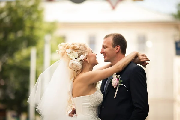 Счастливая невеста с огромными цветами в волосах обнимает шею жениха — стоковое фото