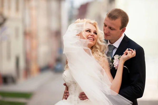 Sorridente sposa bionda si appoggia all'uomo in posa per strada — Foto Stock