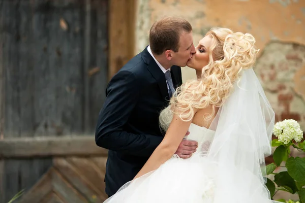 Sposo baci sposa appassionato posa sulla strada — Foto Stock