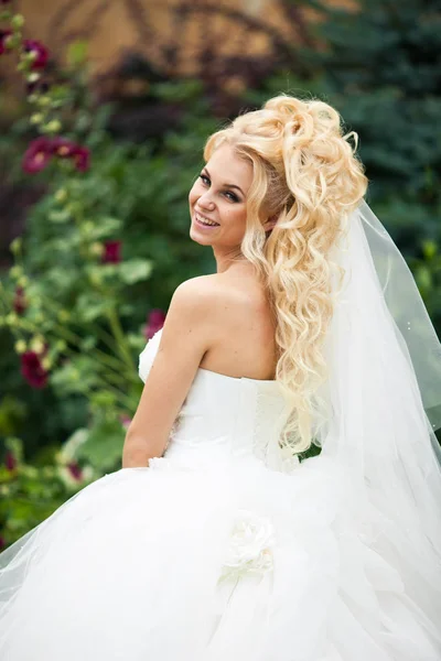 Sposa con lunghi capelli ricci sorride guardando oltre il suo shou delicato — Foto Stock