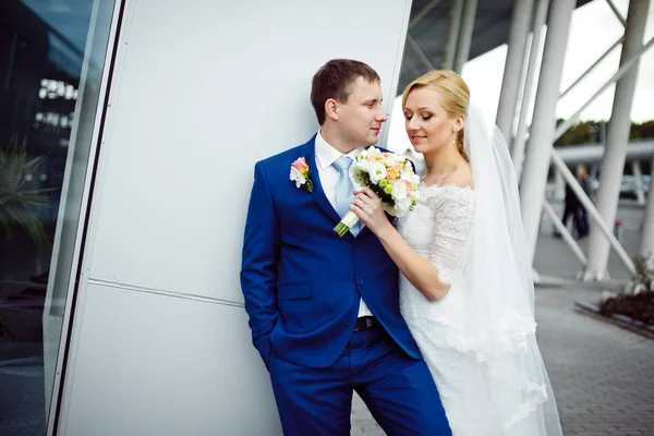 Noiva loira mantém um buquê de casamento na frente de um noivo em — Fotografia de Stock