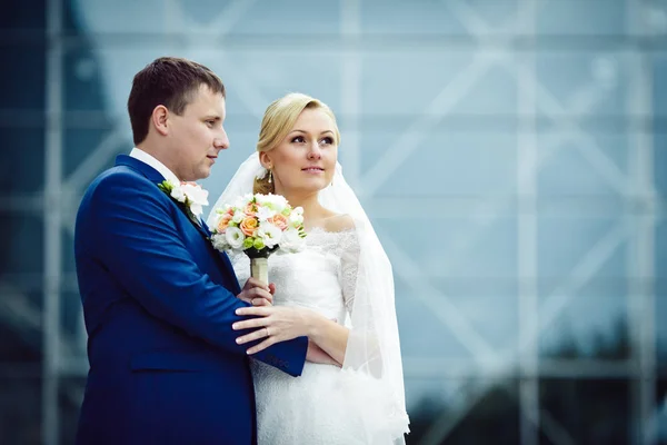 Bräutigam im blauen Anzug umarmt hübsche Braut, während sie in die Höhe schaut — Stockfoto