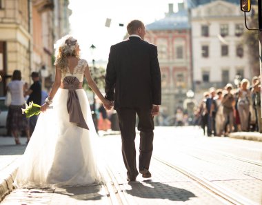 Şık Düğün çifti güneş ışınlarının kalabalık s üzerinde yürür.