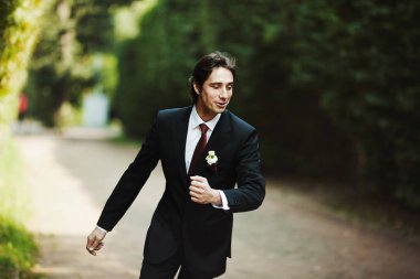 Yakışıklı damat kırmızı kravat yol boyunca çalışır