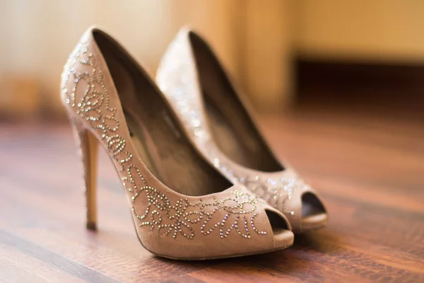 Open toe beige shoes decorated with crystals stand on the floor