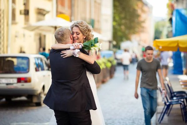 Salti di sposa in abbracci dello sposo che tengono un mazzo di calli — Foto Stock
