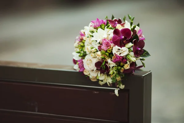 Свадебный букет лежит на спинке скамейки — стоковое фото