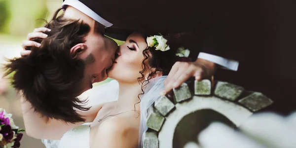 Sposo con i capelli lunghi si capovolge per baciare una sposa seduta o — Foto Stock
