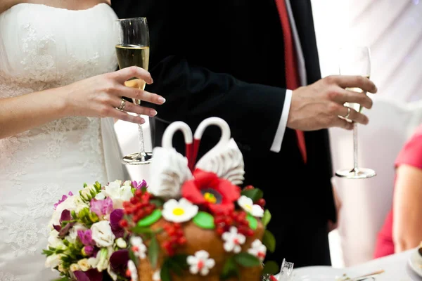 Свадебный хлеб, украшенный лебедями, стоит перед новобрачными — стоковое фото