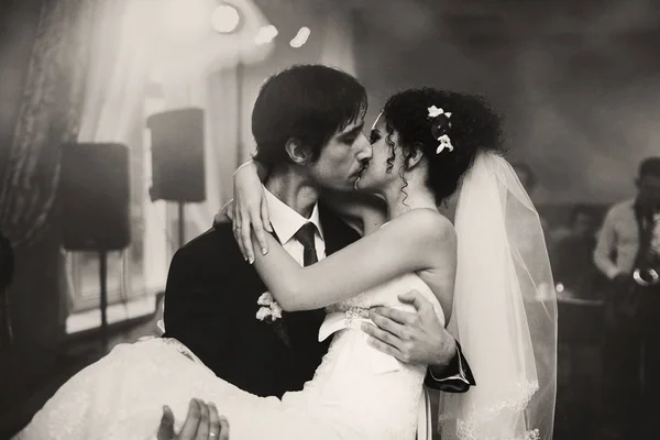 Foto em preto e branco de um noivo beijando uma noiva enquanto segurava — Fotografia de Stock