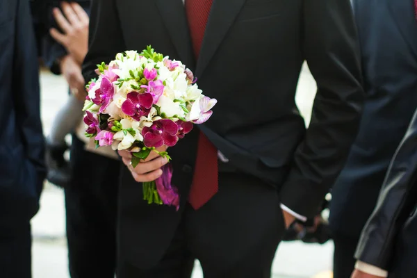 Novio en corbata roja sostiene ramo de boda violeta —  Fotos de Stock