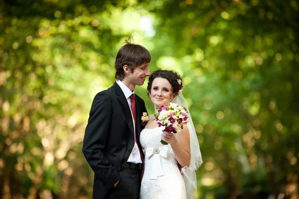 Lockigt brud i en elegant klänning leenden stående bakom en groom — Stockfoto