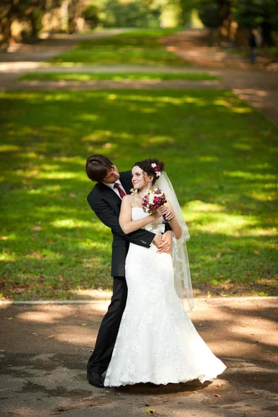 Groom regarde par derrière sur une mariée la serrant dans le trottoir i — Photo