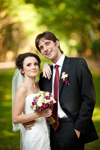 Bräutigam lächelt aufrichtig, während Braut ihre Hand auf seinen Schultern hält — Stockfoto