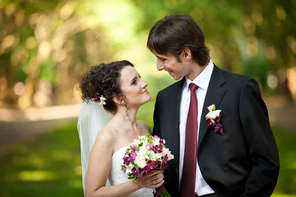 Recém-casados elegantes em roupas elegantes com detalhes vermelhos olhar para eac — Fotografia de Stock