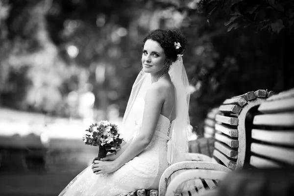 Черно-белая фотография кудрявой невесты, сидящей на белом — стоковое фото