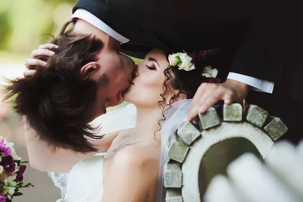 Bride holds her hand over groom's hair while he kisses her upsid — Stock Photo, Image