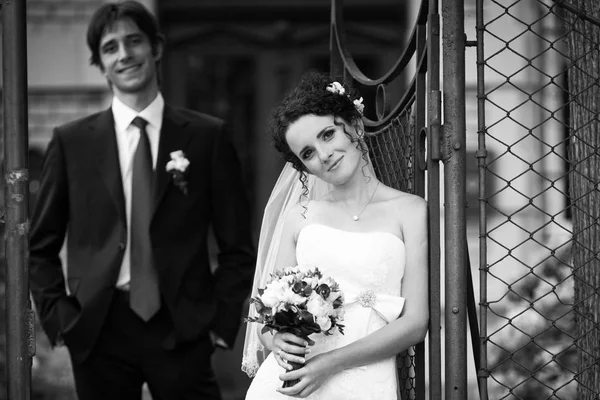 Sweet curly bride leans to the steel fence — Stock Photo, Image