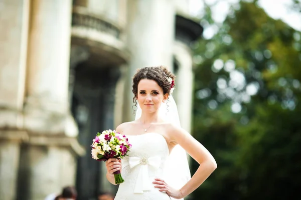 Curly brunette bride holds her hand on the waist posing outside — Stock Photo, Image