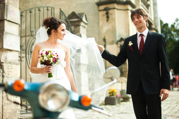 Lustiger Bräutigam fängt Brautschleier ein, während sie auf der Straße stehen — Stockfoto