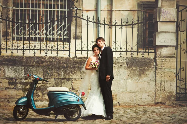 Vrij bruiloft paar staat achter een blauwe scooter — Stockfoto