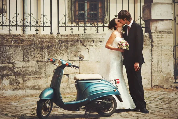Goom kisses a bride standing behind a blue scooter — Stock Photo, Image