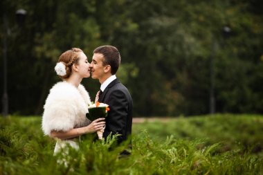 Saçında çiçek ile bir gelin öpüşme damat gülümsüyor
