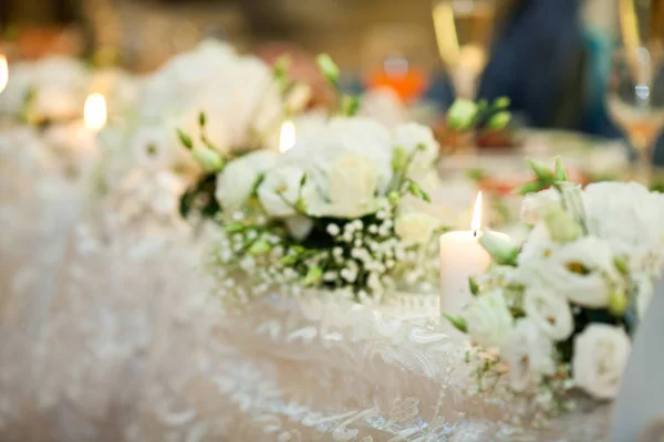 Bougies blanches brûlantes se tiennent entre les bouquets blancs sur le dîner — Photo