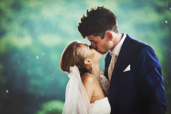 Winzige Braut reicht dem Bräutigam das Gesicht für einen Kuss, der auf dem grünen B posiert — Stockfoto