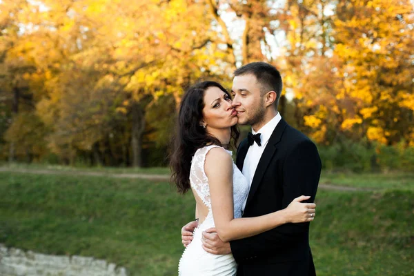 Lustige Braut im reichen Kleid lehnt sich an einen seriösen Bräutigam an — Stockfoto