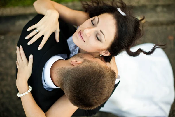 Blick von oben auf einen Bräutigam, der der Braut den Hals küsst, während der Wind bläst — Stockfoto