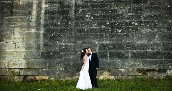 Happy couple se tient derrière un vieux mur de pierre — Photo