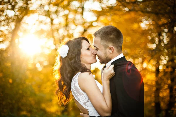 Bride looks funny trying to kiss a groom in an autumn park — Stock Photo, Image