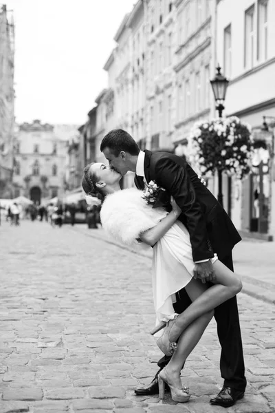 Image en noir et blanc d'un homme embrassant une mariée en robe courte — Photo