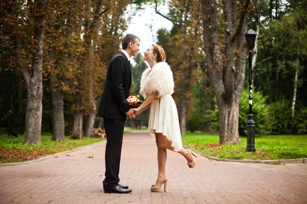 Mosolygó menyasszony öltözött rövid bézs ruha tartja a vőlegény kezét w — Stock Fotó