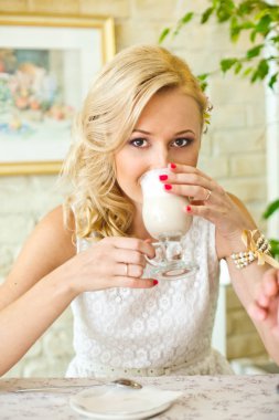 Sarışın beyaz dres latte şirin kafede içecekler.