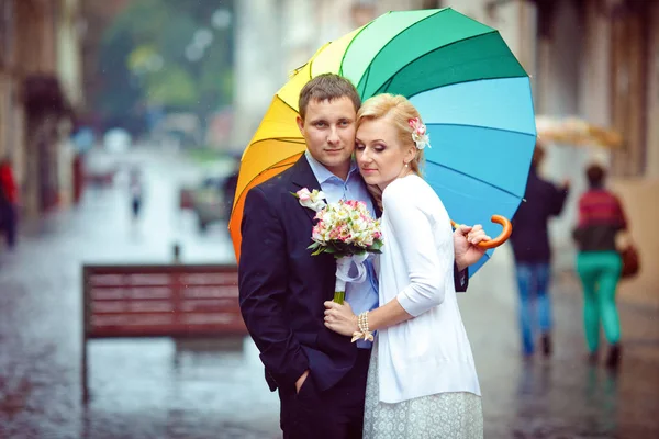 Loira atenciosa se inclina para um homem segurando um guarda-chuva — Fotografia de Stock
