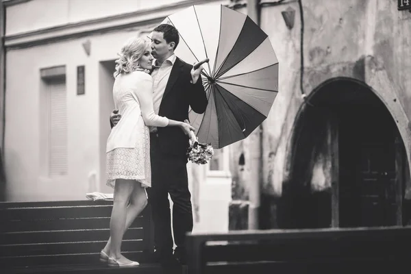 Bride in short dress hugs a groom standing on the wooden bench — Stock Photo, Image