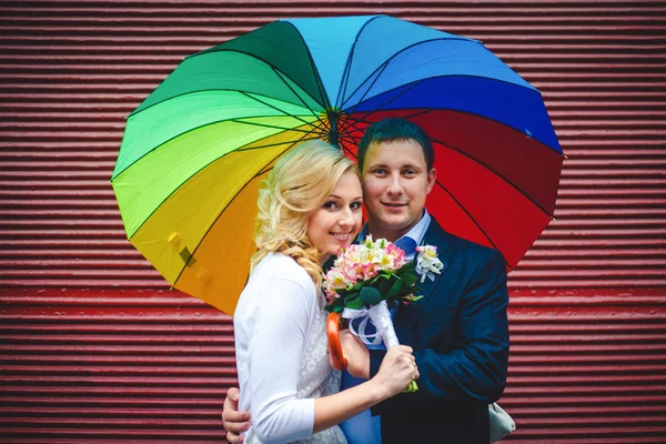 Luminosa immagine di eleganti sposi in posa dietro un muro rosso — Foto Stock