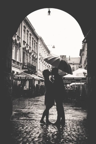 Par kyssar under ett paraply när du står på torget — Stockfoto