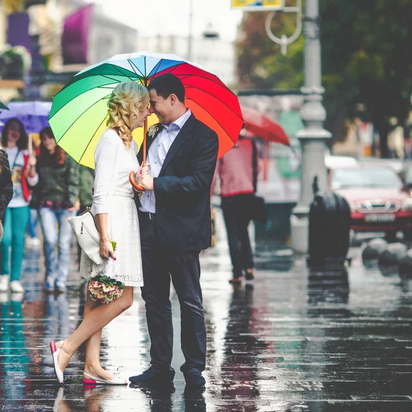 Paret står under färgade paraply på en våt gata — Stockfoto