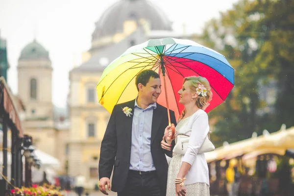 Groom smiles to a bride standing under an umbrella on the city s Stock Image