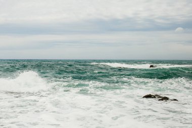 Gri-mavi gökyüzü masmavi deniz kapsar 