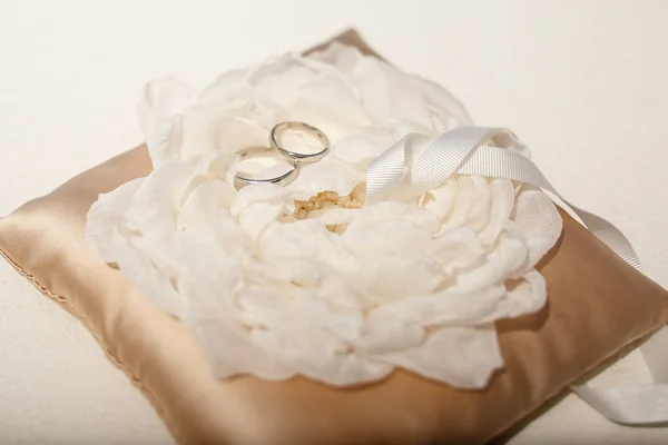 Os anéis de casamento bonitos encontram-se sobre a flor branca prendida à testa — Fotografia de Stock