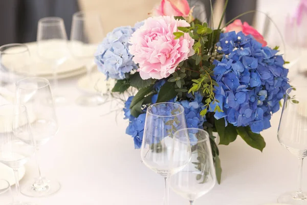 Gevoelige blauwe en roze bloemen staat tussen schijnt glaswerk — Stockfoto